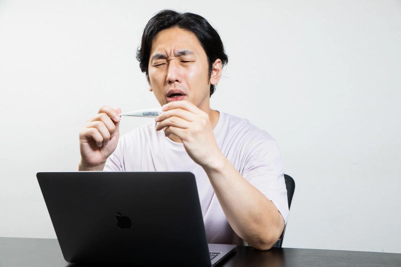 パソコンの前で少し疲れた表情のWebデザイナーが、深呼吸している様子