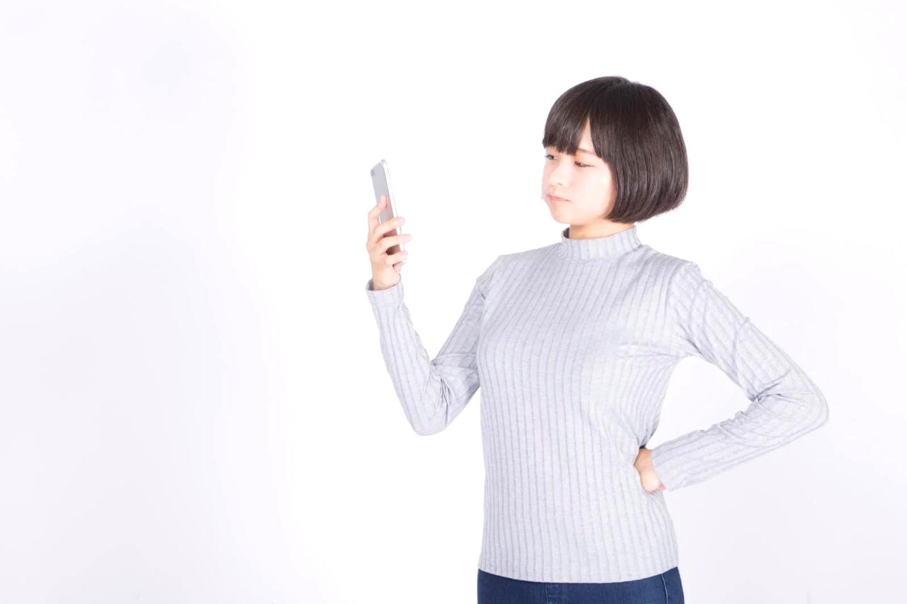スマートフォンを片手に、カフェのテーブルで副業の作業をしている60代男性