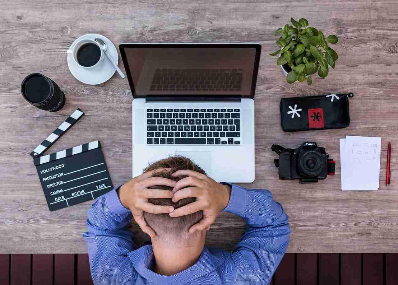 60代のビジネスパーソンがノートPCでXの運用代行を行い、企業のSNS戦略をサポートしている様子