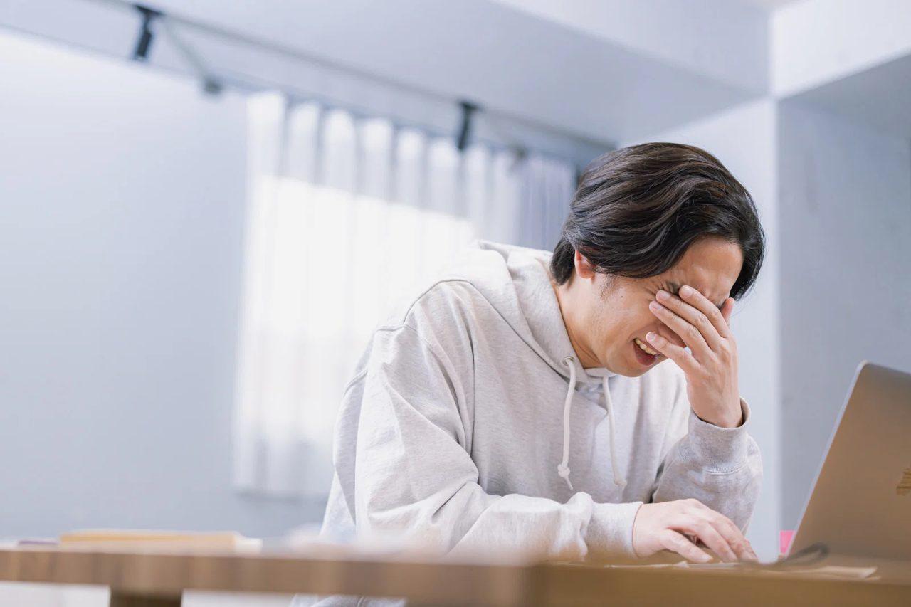 アカウント停止の画面を見て落胆する男性