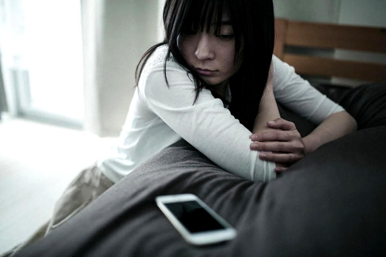 スマホを握りながらTikTok投稿に悩む初心者がうつむいている様子