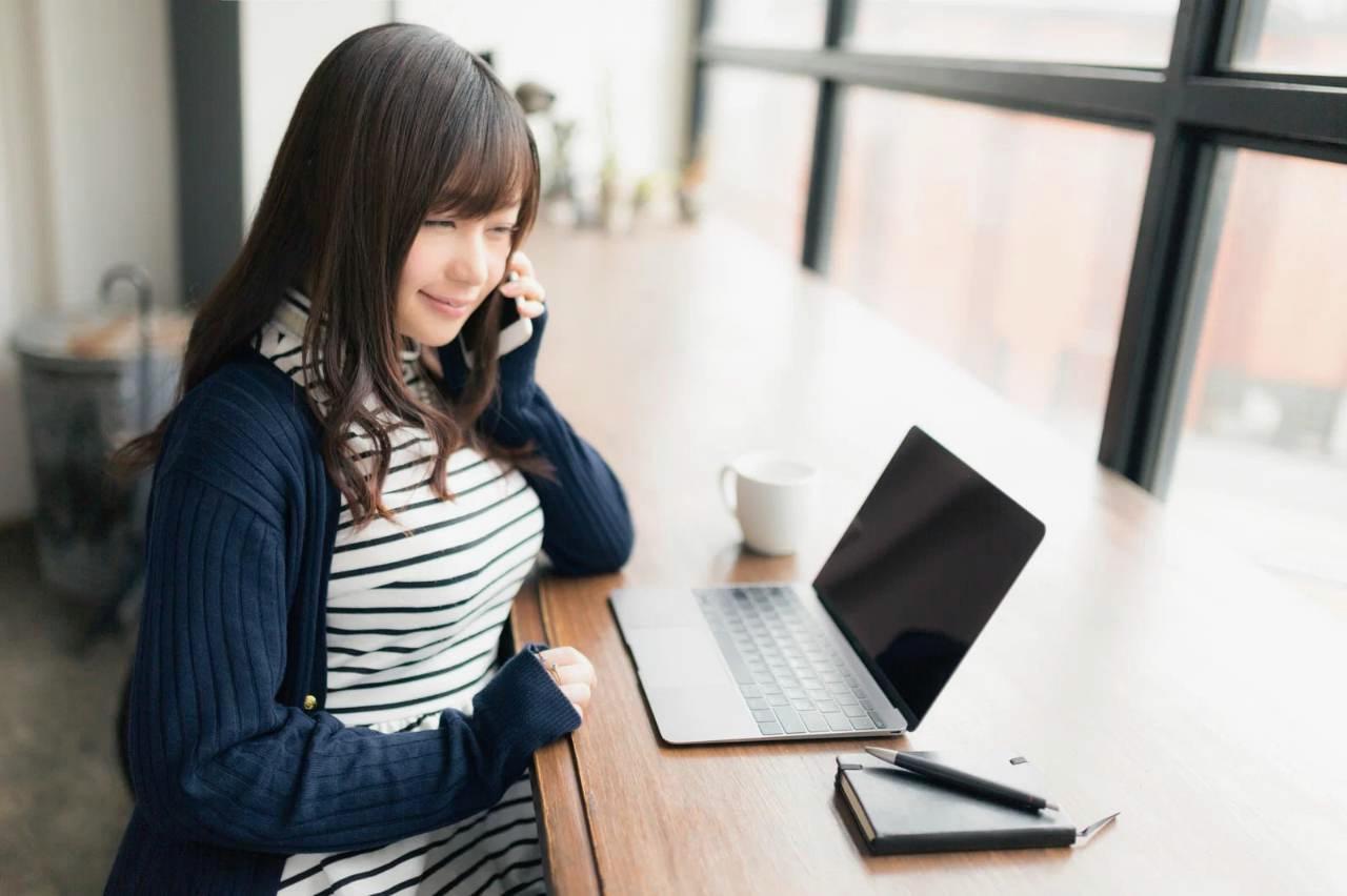 パソコンとノートを並べて、Wixのテンプレートを編集しながら手書きのスケッチを見比べる高齢者の手元