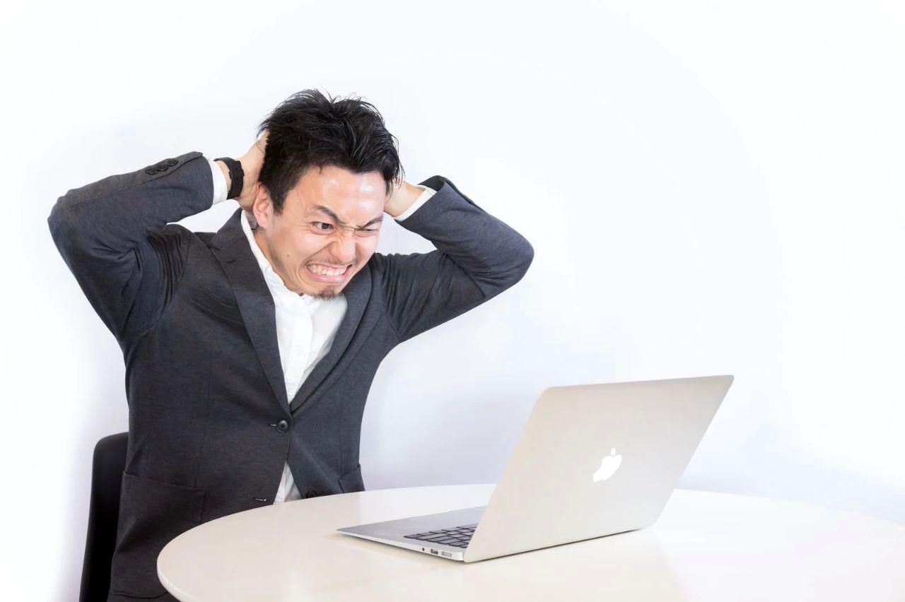 パソコンの前に座り落ち込む男性。Bloggerでの雑記ブログ運営に挫折してうつむく姿を表現した画像。